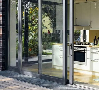 Black aluminum sliding doors connecting a kitchen and patio